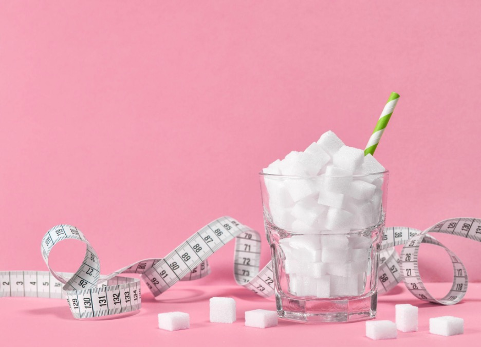 A glass of sugar cubes and a straw and measuring tape.