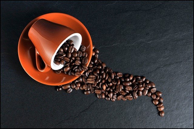 Coffee beans spilling from a mug.