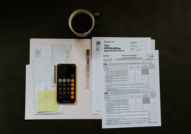 All bills, calculator and coffee mug placed on the table.