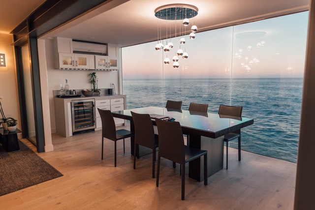Lavish sea facing dinning room with hanging lights and minimum furniture.