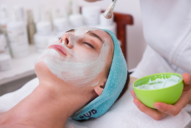 A woman applying a face pack on the customers face.