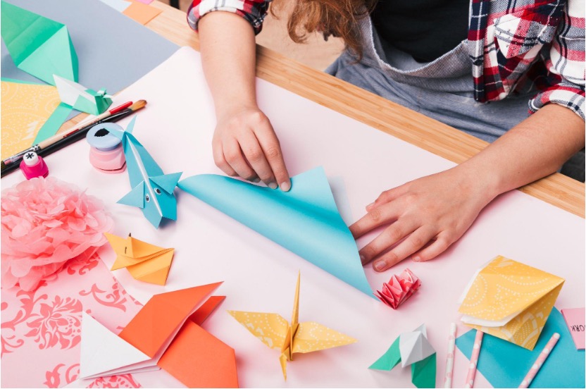 A boy folding an origami sheet.