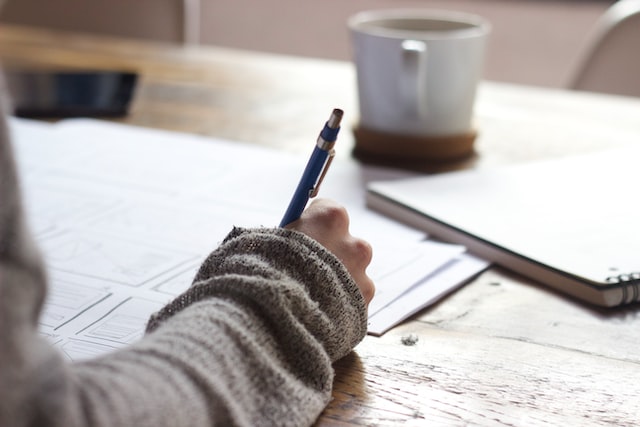 A woman writing with a pen on a paper.