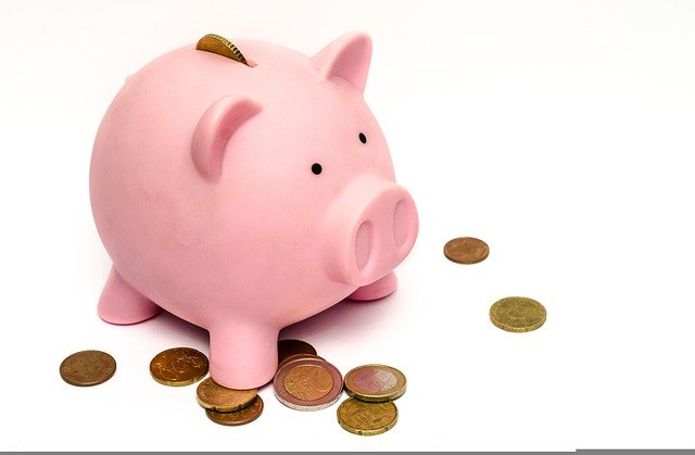 A pink piggy bank with coins around.