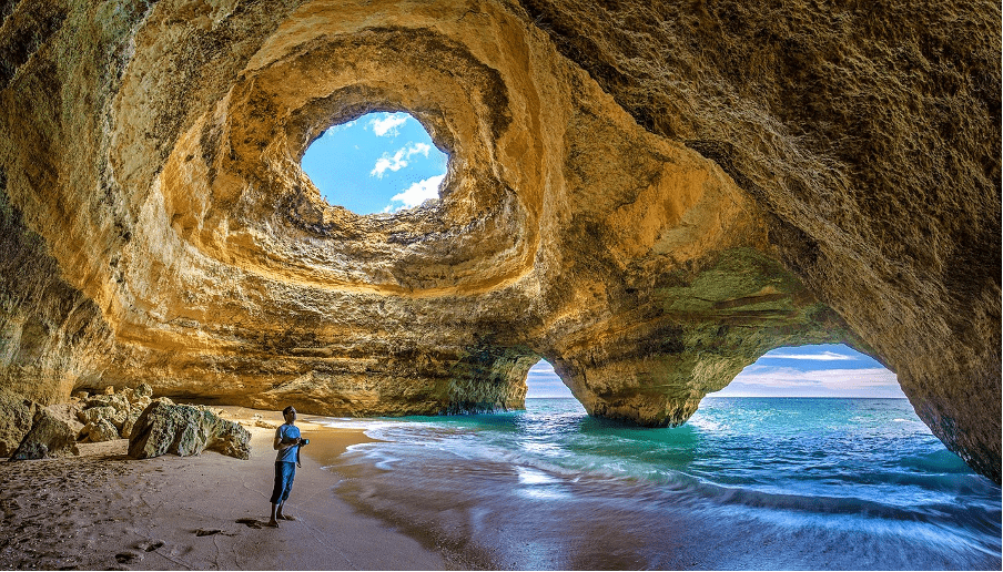 A boy standing near a ocean.